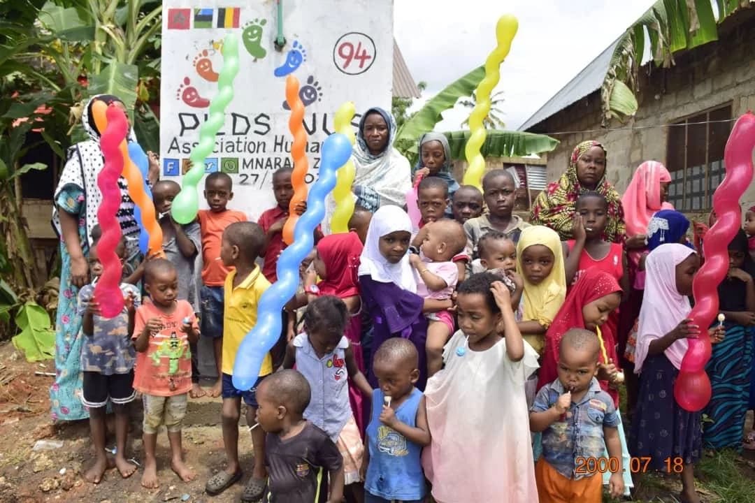 Foule d'enfants et d'habitants devant le point d'eau n° 94 à Zanzibar, ballons colorés